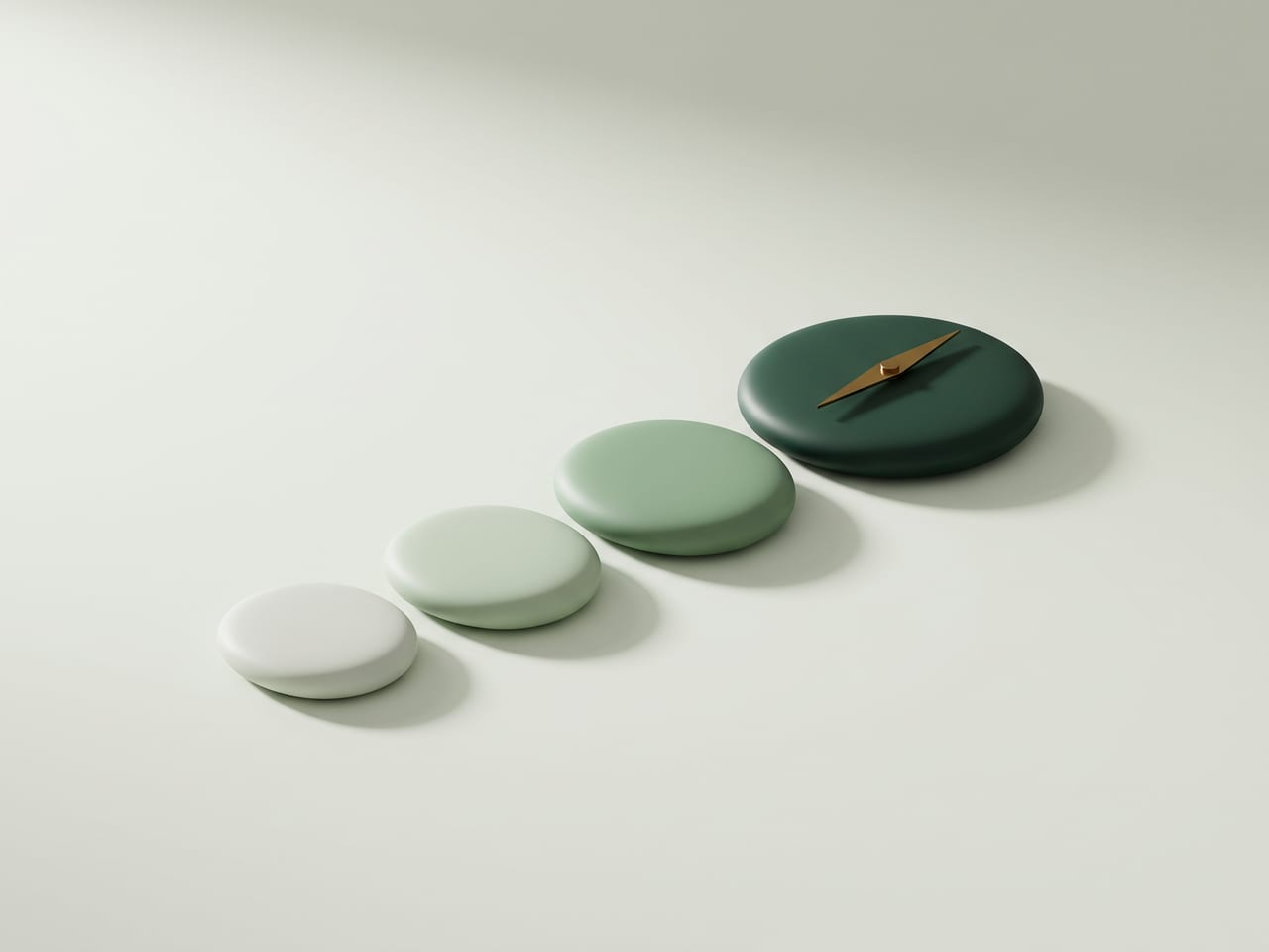 Four rounded stones deepening from pale sage to dark pine green, with a brass compass needle resting on the last.